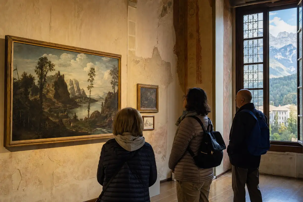 Visitatori osservano un dipinto di paesaggio in una sala museale, con vista sulle montagne da una grande finestra